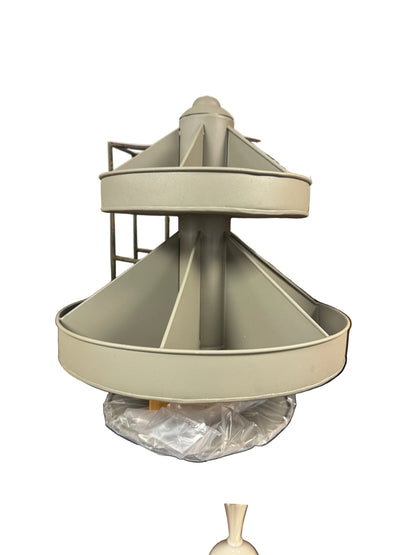 A light gray plastic kitchen accessory, likely a strainer basket or filter cone, resting on a black utility table in a storage room with cardboard boxes in the background.