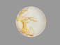 A round white ceramic plate with a gold seashell and coral-like line art design, photographed from above on a textured gray surface.